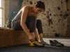 Best Beginner Climbing Shoes the Gym Won’t Sell You Beginner climber lacing up La Sportiva Finale shoes on a gym bench before a top-rope session