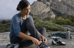 Best Climbing Shoes for Women That Won’t Wreck Your Feet Woman lacing La Sportiva Katana Lace climbing shoes at the base of a granite crag before her first route