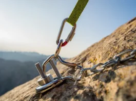 Secure connection of a modern PAS (Personal Anchor System) to a fixed rock climbing anchor with a locking carabiner, representing the ultimate guide to anchor chains.