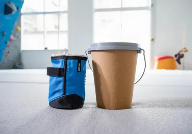 Chalk bag versus chalk bucket comparison shown side-by-side in a climbing gym setting, asking which is right for your climb.