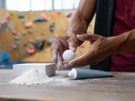 A collection of different climbing chalk types (loose, block, ball, liquid) arranged on a wooden table, with diverse hands selecting a chalk ball, symbolizing mastering climbing chalk.