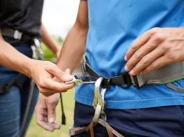 Climber performing safety check on partner's correctly fitted harness, illustrating fit secrets and avoiding mistakes.