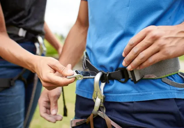 Climber performing safety check on partner's correctly fitted harness, illustrating fit secrets and avoiding mistakes.