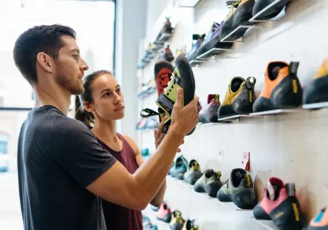 Diverse climbers choosing the right fit from a selection of La Sportiva climbing shoes in a gear shop size guide context.