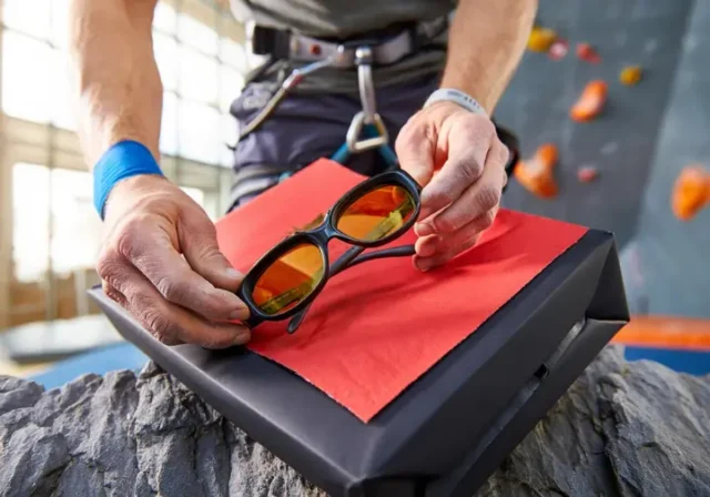 Climber happily unwrapping unique rock climbing gifts they actually want, like belay glasses or a chalk bag.