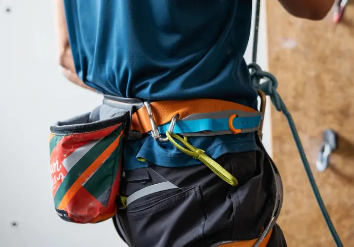 Understanding chalk bags: Close-up of a climber wearing a chalk bag attached to their harness while rope climbing.