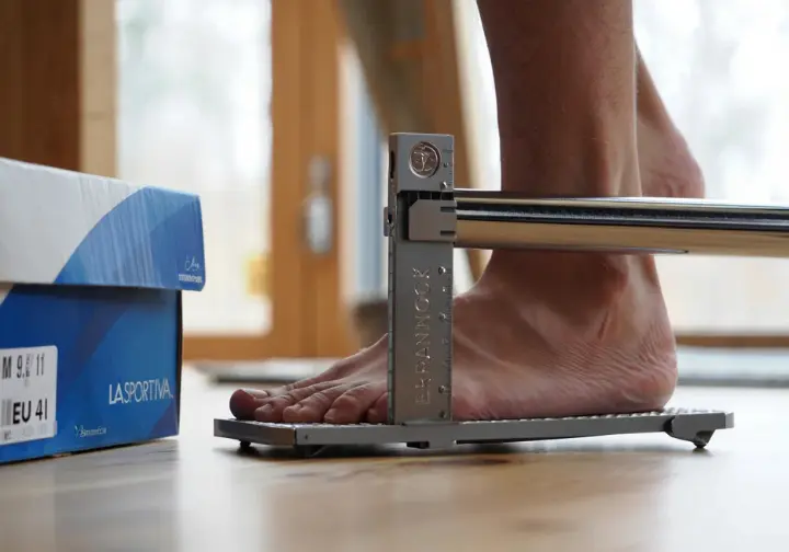 Foot being measured on Brannock device next to La Sportiva shoe box showing EU/US sizes for understanding sizing.