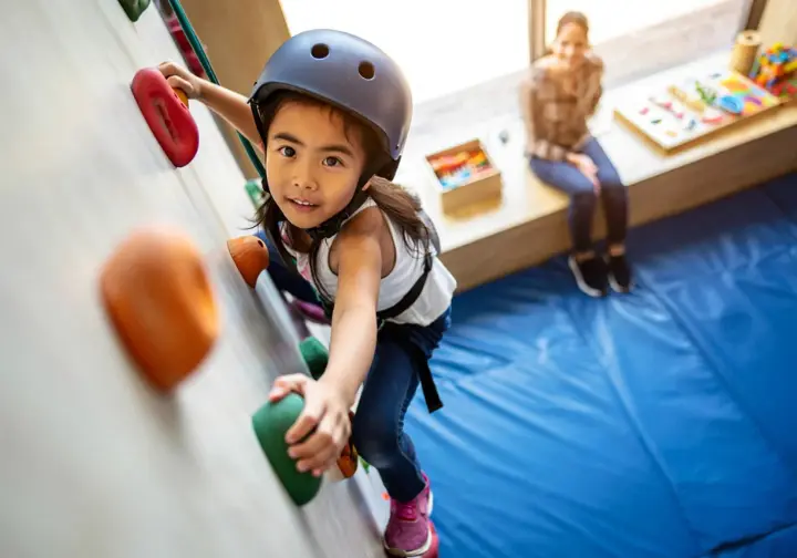Child actively engaged on a home children's climbing wall, showcasing physical, cognitive, and emotional benefits that make it more than just playtime.
