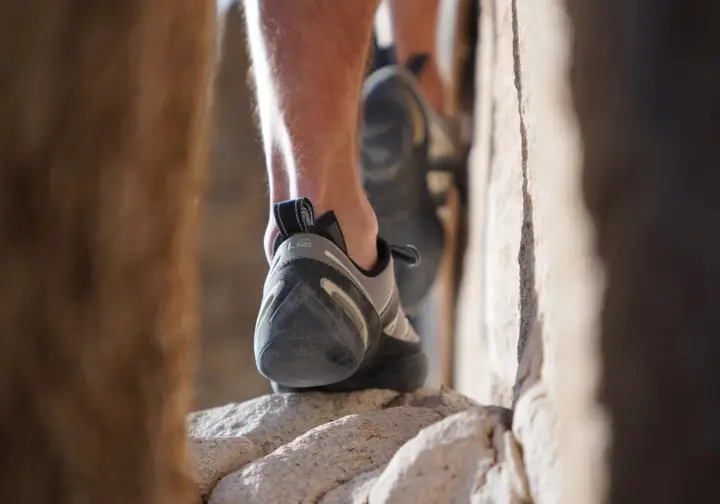 Climber's foot in a well-fitted shoe precisely edging on a small rock hold, showing why fit matters critically.