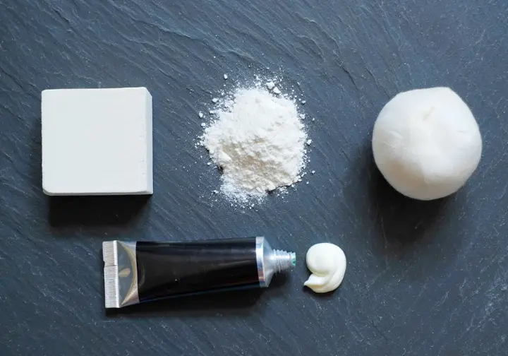 Flat lay of different climbing chalk types (loose, block, ball, liquid) arranged like a palette on slate, for navigating various chalk options.