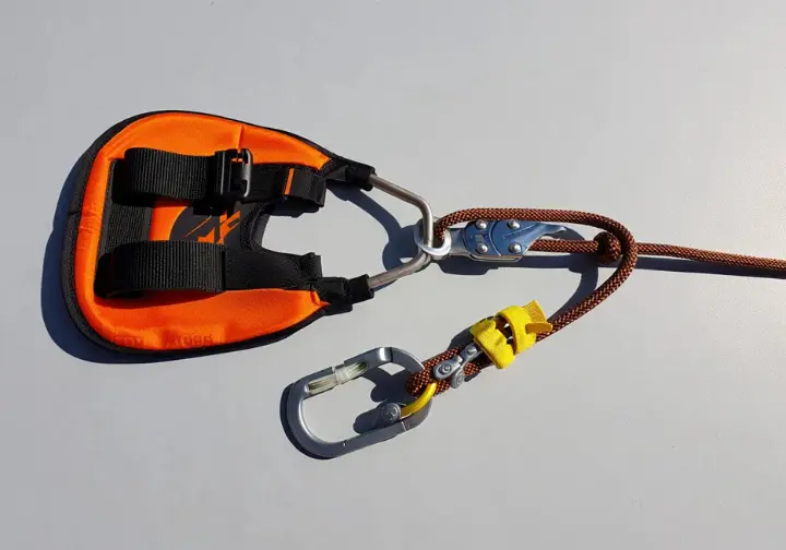 Core tree climbing system components (saddle, rope, carabiner, friction control) assembled correctly.