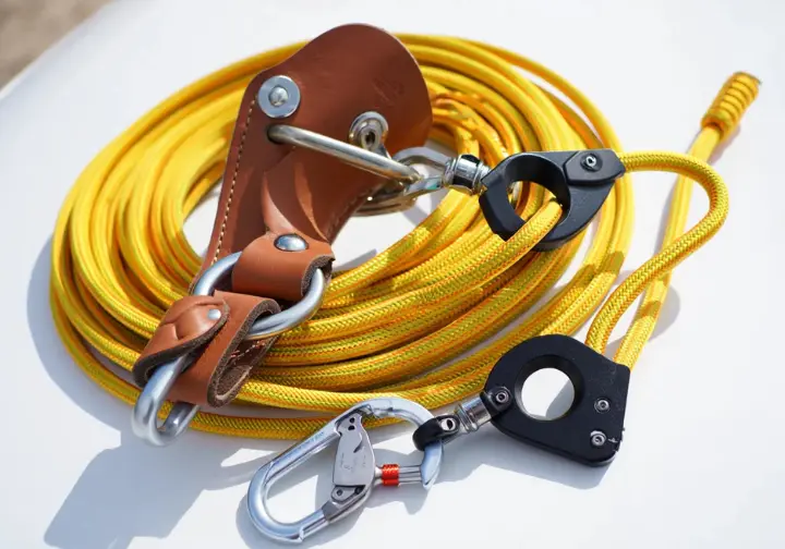 Core tree climbing system components (saddle, rope, carabiner, friction control) interconnected.
