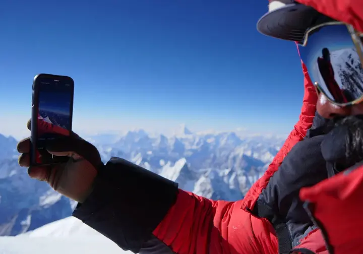 Climber reality of how long phones last on Everest: Climber quickly taking a summit photo before phone battery dies.