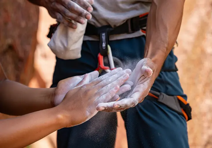 Diverse climbers' hands demonstrating proper chalk application from a chalk bag, unveiling grip secrets for mastering climbing chalk.