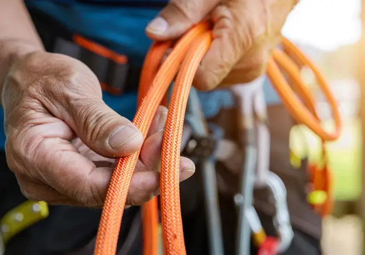 Arborist demonstrating critical safety knowledge by meticulously inspecting a climbing rope before use.