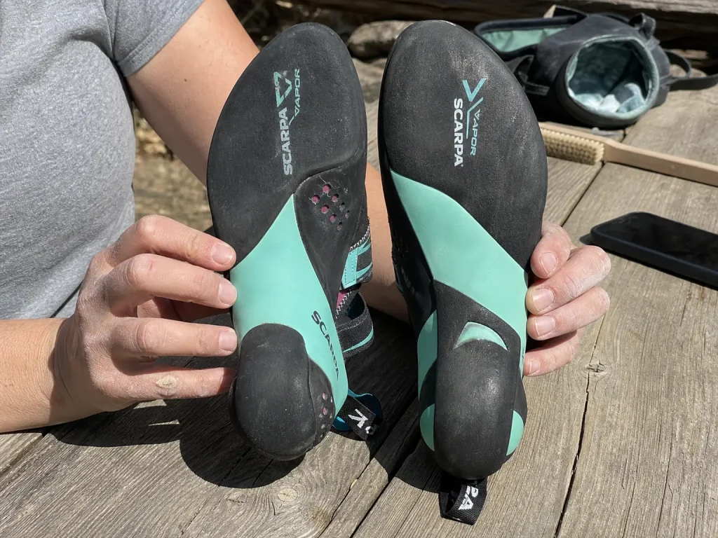 Close-up comparison of a women's Scarpa Vapor V climbing shoe sole held up beside a men's version