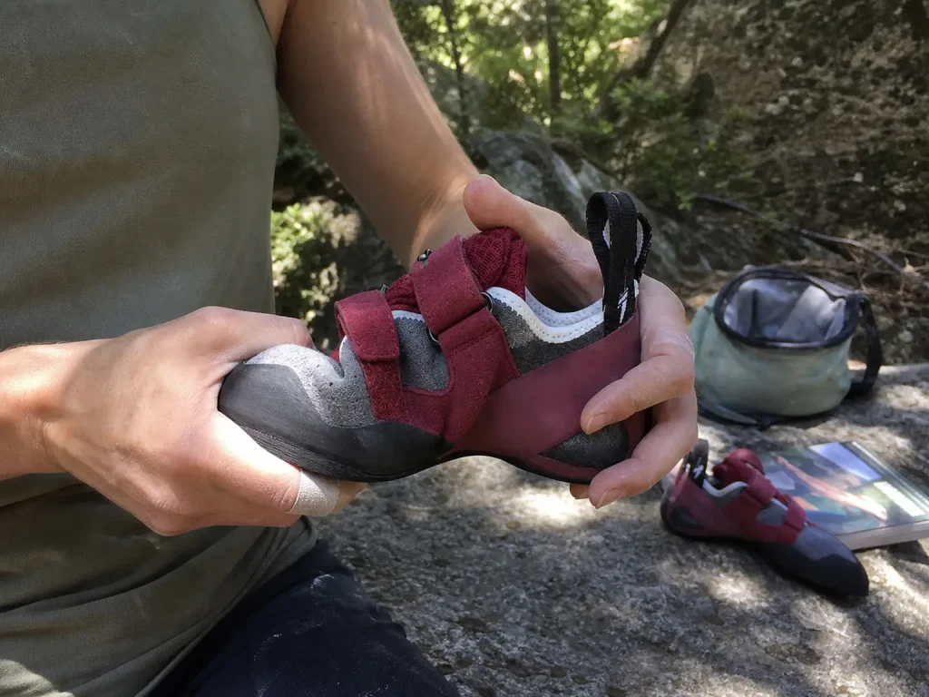 Evolv Elektra women's climbing shoe flexed by hand to show midsole stiffness and downturn