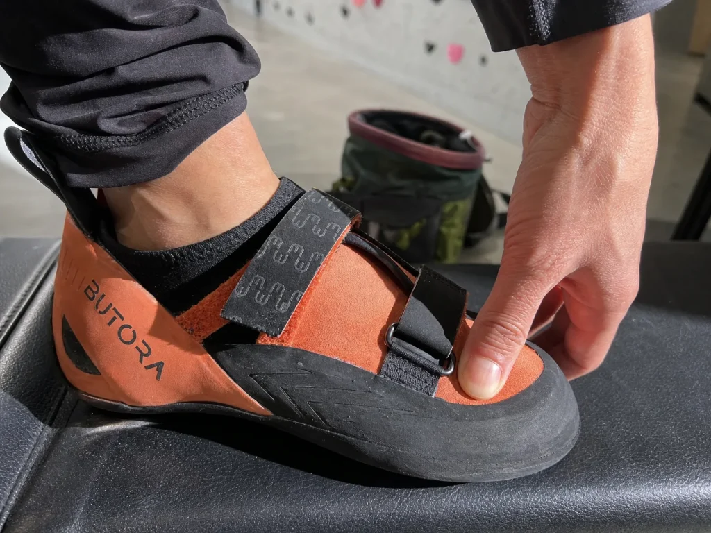 Climber pressing a thumb at the toe of a Butora Endeavor shoe to check beginner fit