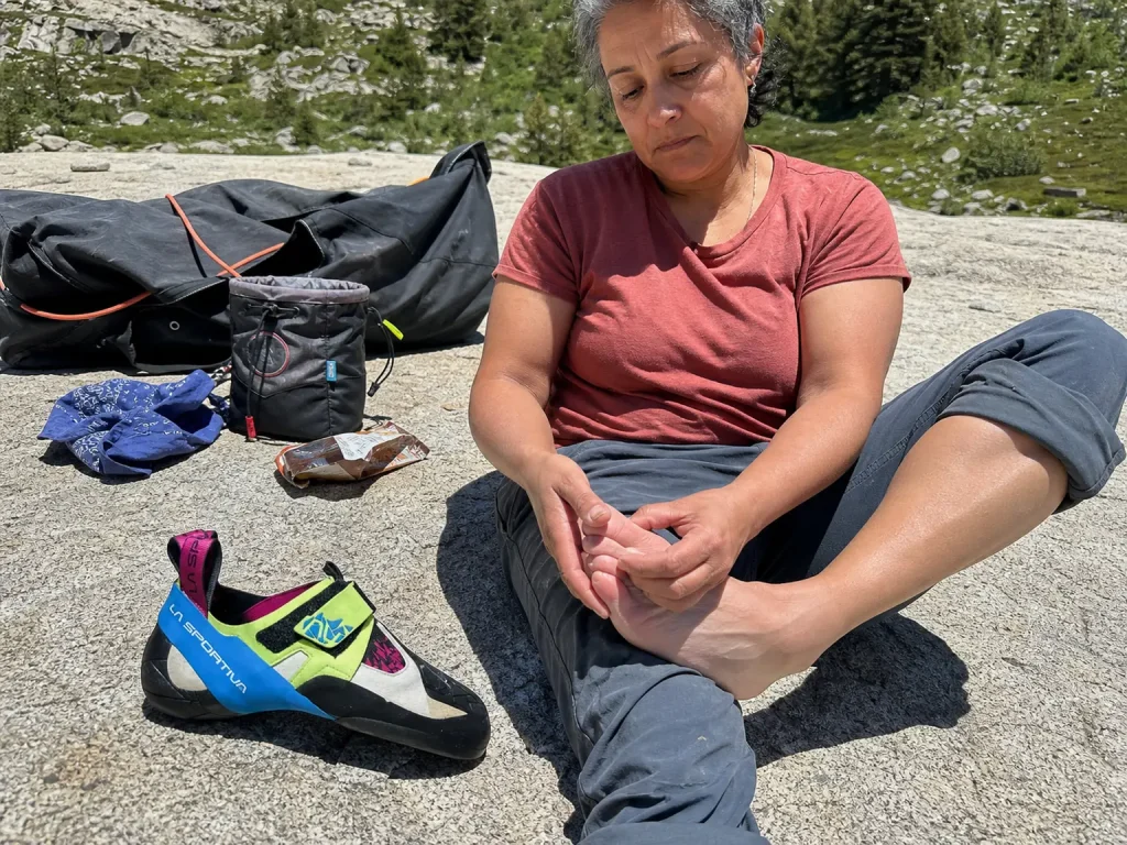 Barefoot climber resting beside an aggressive La Sportiva Skwama shoe after a long bouldering session