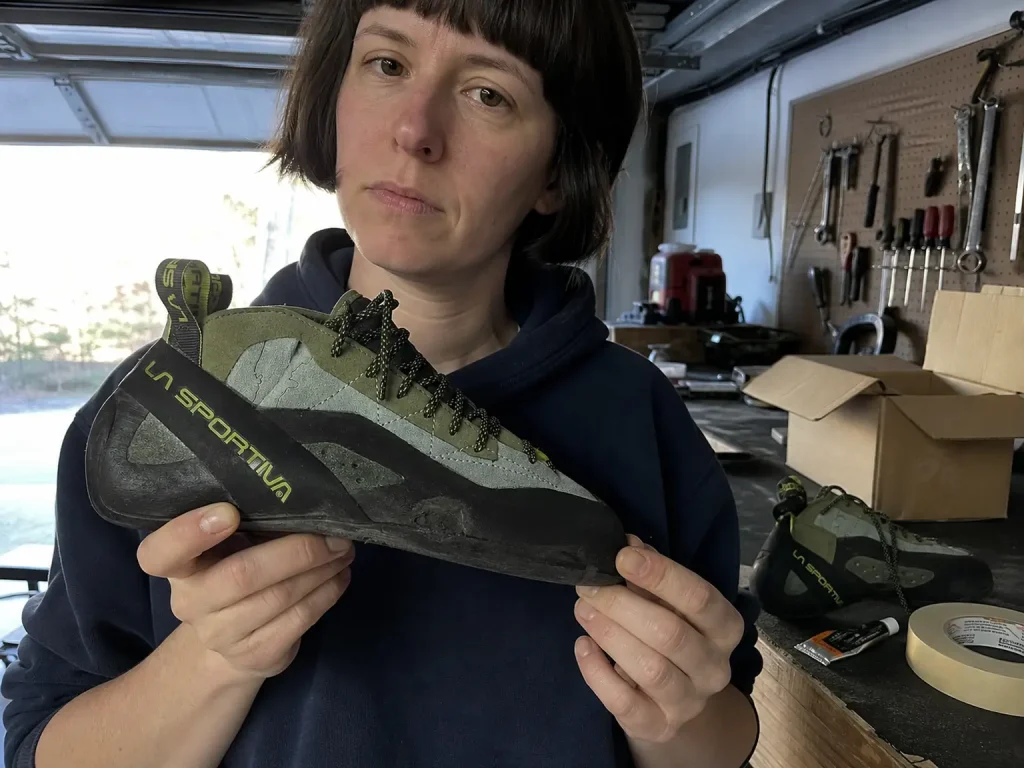 Worn La Sportiva TC Pro climbing shoe with thinning toe rubber held up before a resole