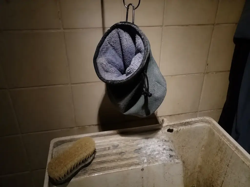 Chalk bag turned inside out and hanging open to air-dry over a utility sink after washing