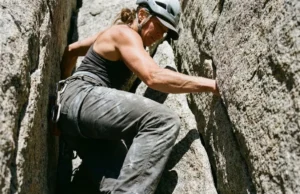 Best Ladies Climbing Pants: Sustainable & Durable Picks A female rock climber stemming a granite crack wearing durable technical climbing pants.