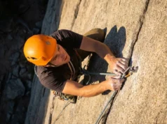 Climbing Helmet Guide: Best Picks by Head Shape & Tech A climber wearing a modern climbing helmet ascending a steep granite rock face during sunset.