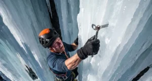 Lightest Ice Screws Ranked: Weight vs. Durability Alpinist placing an ice screw on a steep vertical frozen waterfall.