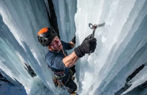 Lightest Ice Screws Ranked: Weight vs. Durability Alpinist placing an ice screw on a steep vertical frozen waterfall.
