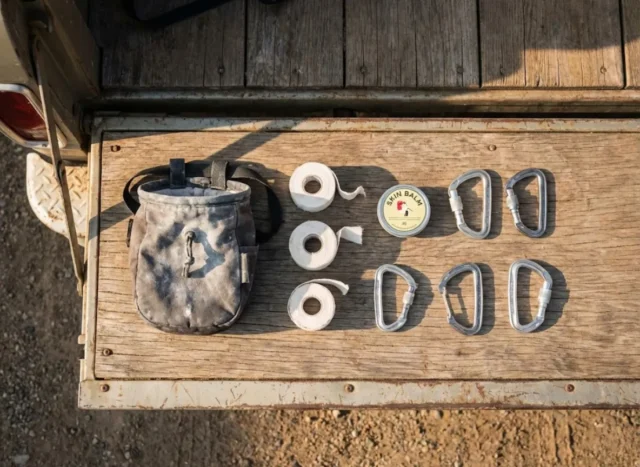 rock-climber-gift-ideas-fail-safe-picks-ranked A curated collection of essential rock climbing gear including chalk, tape, and carabiners arranged neatly on a wooden surface.