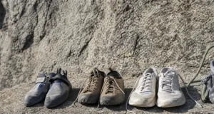 Rock Climbing Sneakers Are Really 3 Different Shoes Three types of footwear lined up on a granite ledge — a flat climbing shoe, an approach shoe, and a street sneaker