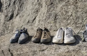 Rock Climbing Sneakers Are Really 3 Different Shoes Three types of footwear lined up on a granite ledge — a flat climbing shoe, an approach shoe, and a street sneaker