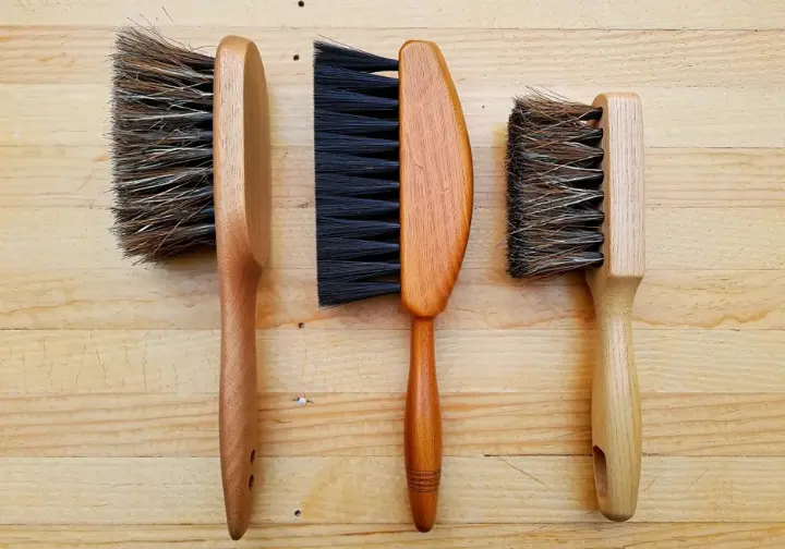 Flat lay of different rock climbing brushes showcasing various bristle materials (boar's hair, nylon, horsehair) and handle designs, explaining the anatomy for performance