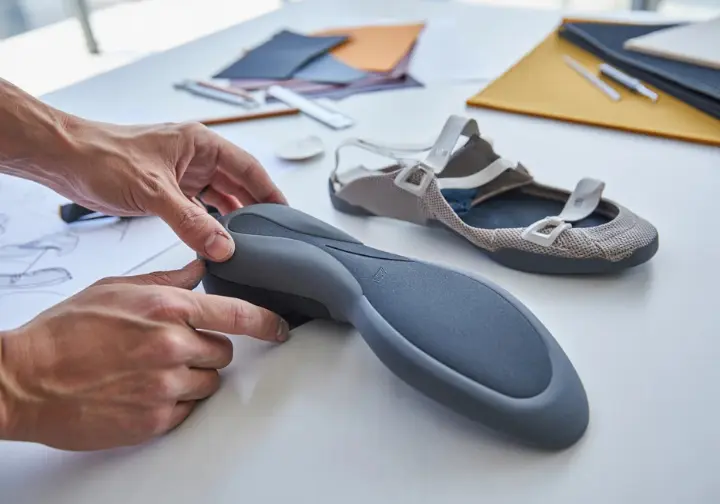 Deconstructed rock climbing shoe showing its key components (sole, rand, upper, closure) laid out, explaining the anatomy of this performance tool.