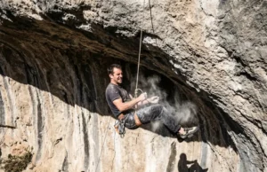 Best Petzl Climbing Harness: Gym, Trad, or Alpine? A rock climber falling on a sport route, suspended by a Petzl climbing harness against a limestone wall.