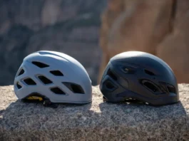 Two rock climbing helmets, one lightweight and one durable, resting on a rock surface, illustrating the choice between lightweight and durable rock climbing helmets.