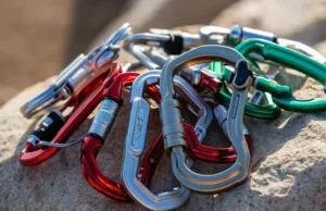 Locking Carabiners Explained: Screw-Gates to Auto-Locks An assortment of modern locking carabiners including screw-gate, twist-lock, and triple-lock types, displayed on a rock surface, highlighting the various mechanisms for climbing safety.
