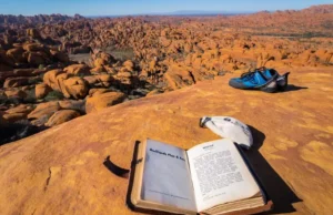 Bouldering in Rocklands: Complete Plan & Beta A climber's guidebook and gear laid out on a rock overlooking the expansive, sunlit sandstone bouldering landscape of Rocklands, symbolizing a complete plan for bouldering in Rocklands.