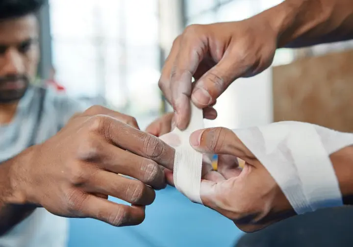Close-up view of hands meticulously demonstrating a step-by-step finger taping technique for climbing, crucial for mastering how to tape fingers correctly.