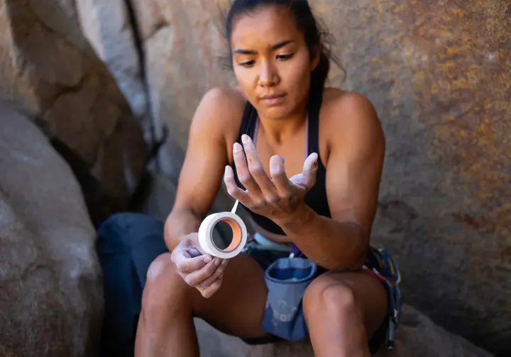 Climber strategically considering when and when not to tape their fingers for climbing, illustrating the appropriate and thoughtful use of finger taping techniques.