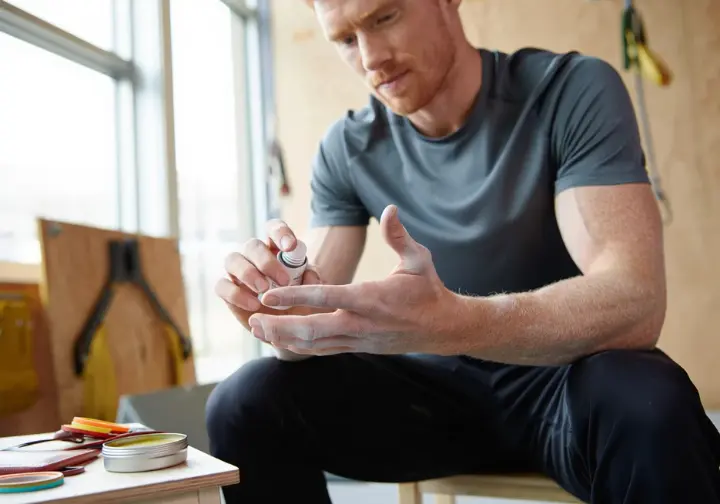Climber practicing holistic finger health using a finger extensor trainer, emphasizing comprehensive care beyond simply knowing how to tape fingers for climbing.