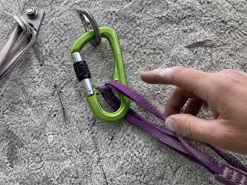 Anti-cross-load belay carabiner sitting correctly on its major axis at an anchor master point