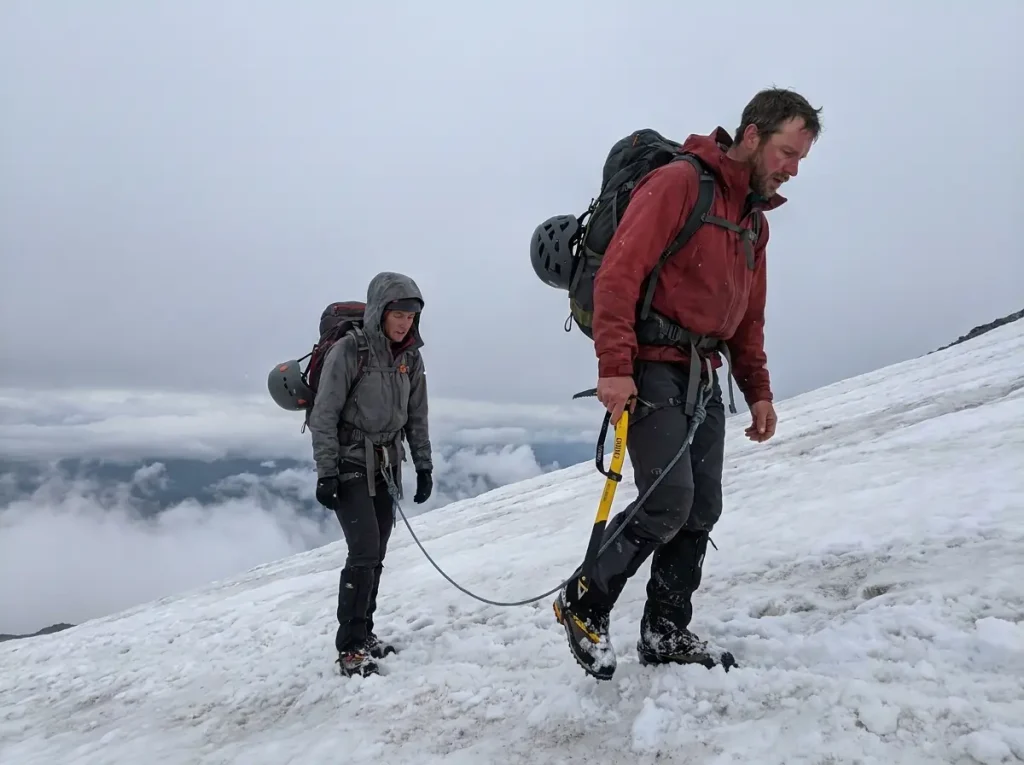 Tired roped climbers descending Rainier's snow slope after turning around below the summit