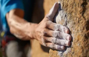The Science of Grip: An Ultimate Climbing Chalk Guide A close-up of a climber's chalked hand gripping a rock hold, illustrating the science of grip for the ultimate climbing chalk guide.