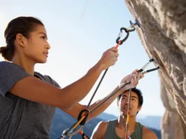 Two rock climbers, male and female, demonstrating quickdraw use on a sunny rock face, highlighting how to choose and clip quickdraws for climbing safety.