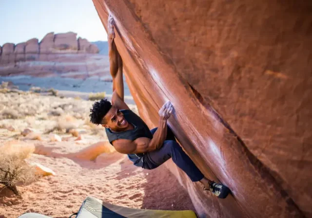 Climber at the crux of a sandstone boulder problem in Red Rocks, illustrating the article's coverage of bouldering red rocks from V0 to V-Hard with insider tips.