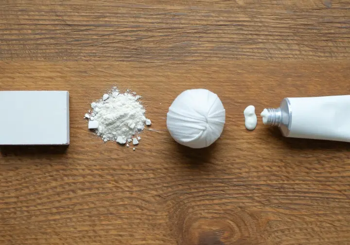 An overhead view of various climbing chalk types, including a block, loose powder, a chalk ball, and liquid chalk, laid out as a guide to a climber's chalk arsenal.