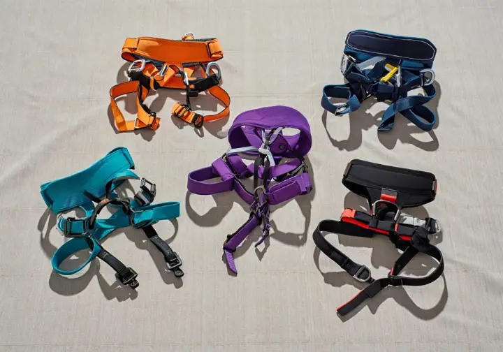 A collection of top-rated women's climbing harnesses from various brands displayed on a neutral background.