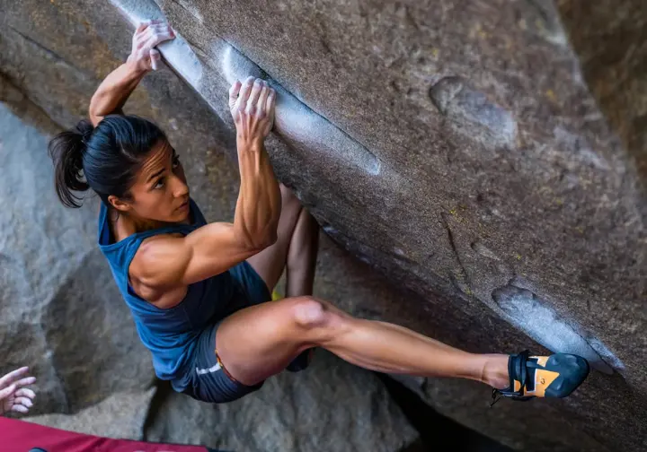 Female climber executing a technical balance move on a granite slab at Boat Rock bouldering area, showcasing the unique, skillful climbing experience required.