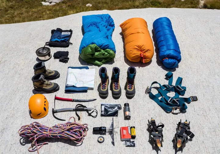 Flat lay of essential mountaineering gear including rope, ice axe, crampons, and tent, for Sierra Nevada expeditions.